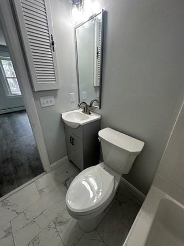 bathroom with toilet, marble finish floor, vanity, and baseboards
