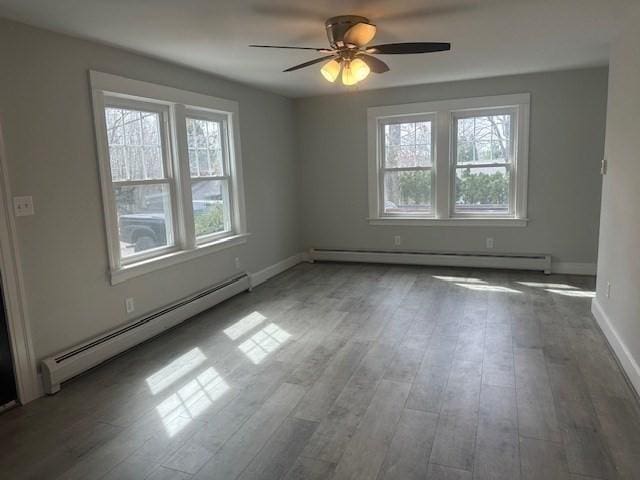 empty room featuring wood finished floors, ceiling fan, baseboard heating, and baseboards