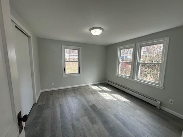 unfurnished bedroom featuring baseboards, baseboard heating, and dark wood finished floors