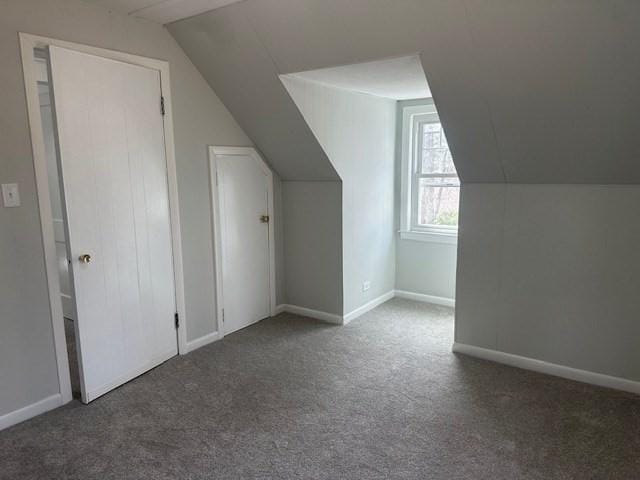 additional living space featuring carpet, vaulted ceiling, and baseboards