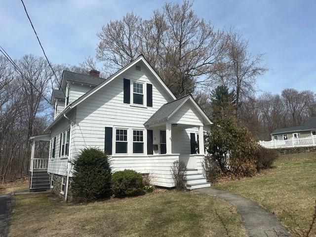 bungalow-style house featuring stairway, a chimney, a porch, and a front lawn