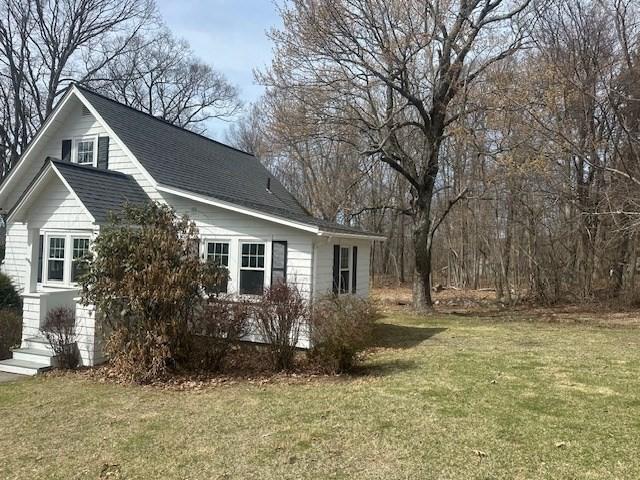 view of side of home featuring a lawn and a shingled roof