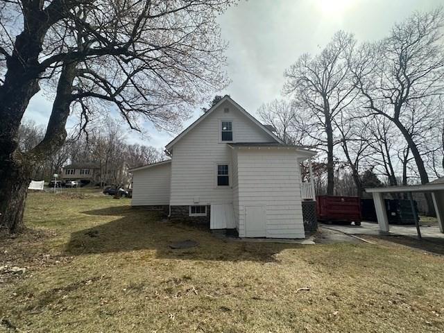 view of side of home featuring a carport and a yard