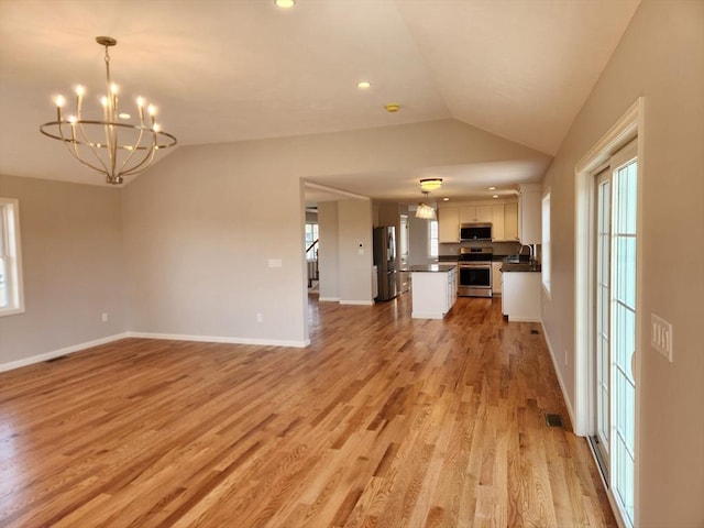 53 Kelly Ln, Lynn, MA 01904 - unfurnished living room with an inviting chandelier, a sink, light wood-style floors, baseboards, and vaulted ceiling