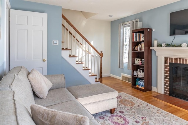 living room with visible vents, wood finished floors, stairway, a fireplace, and baseboards