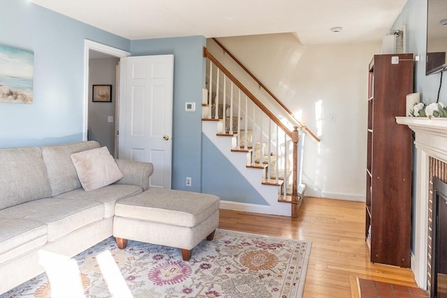 living room featuring stairs, wood finished floors, baseboards, and a fireplace