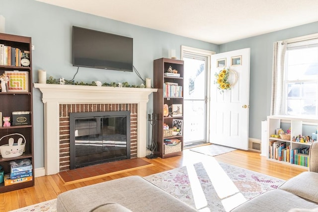 living area with a brick fireplace and wood finished floors