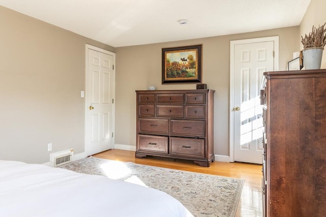 bedroom with light wood-style floors, visible vents, and baseboards