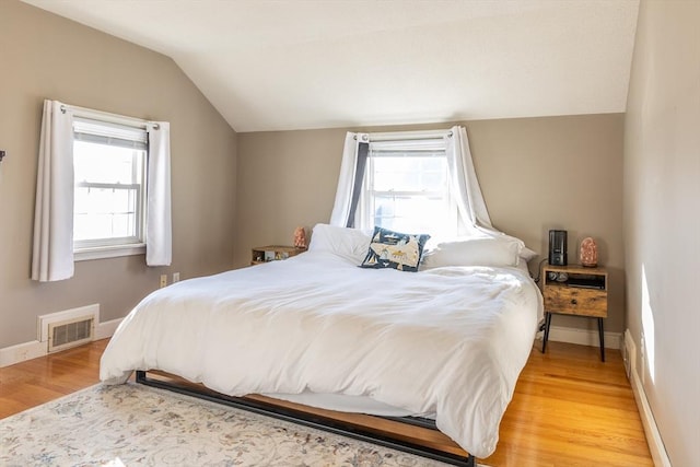 bedroom featuring vaulted ceiling, multiple windows, visible vents, and light wood finished floors