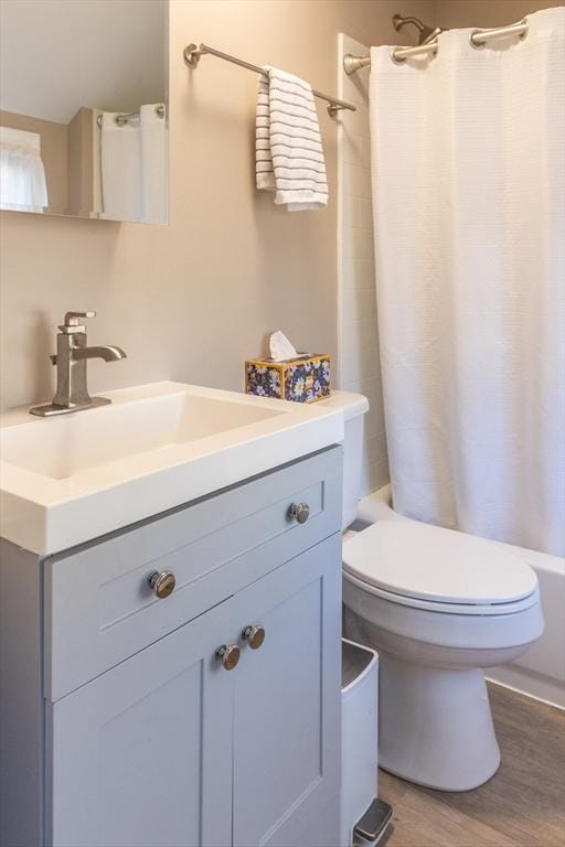 full bath featuring vanity, toilet, wood finished floors, and shower / tub combo with curtain