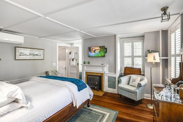 bedroom featuring a wall mounted AC, wood finished floors, and a fireplace