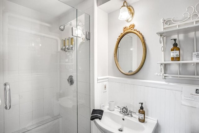 bathroom with a sink, a shower stall, and wainscoting