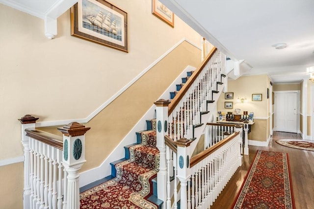 stairs featuring wood finished floors, ornamental molding, and baseboards