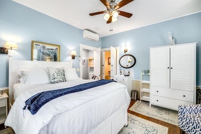 bedroom with a wall unit AC, wood finished floors, and a ceiling fan