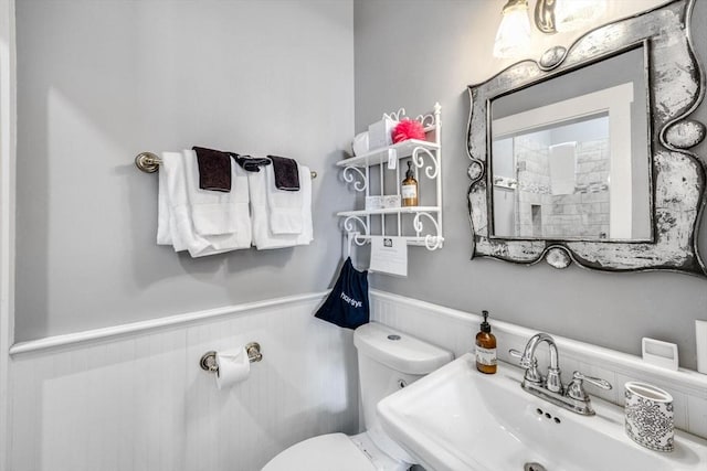 bathroom featuring wainscoting, a sink, and toilet