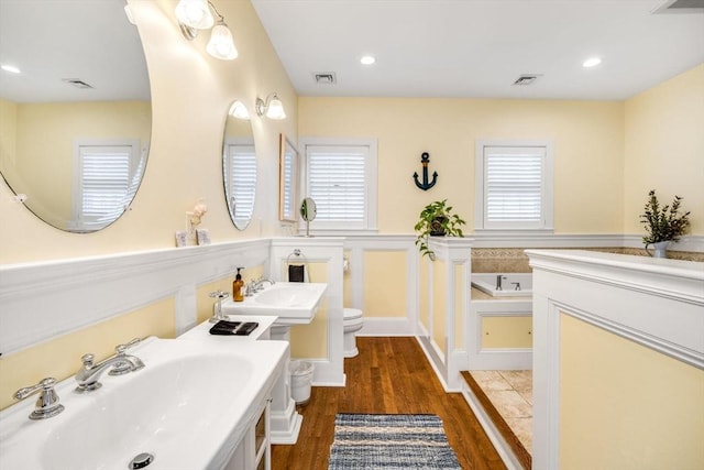 bathroom featuring wood finished floors, toilet, a garden tub, and recessed lighting