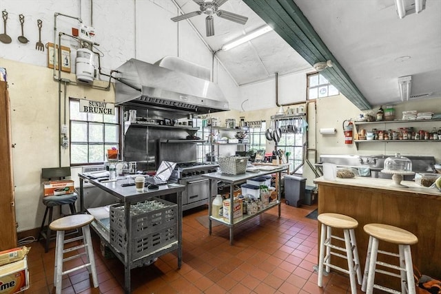 kitchen featuring wall chimney exhaust hood, high vaulted ceiling, a ceiling fan, tile patterned floors, and beamed ceiling