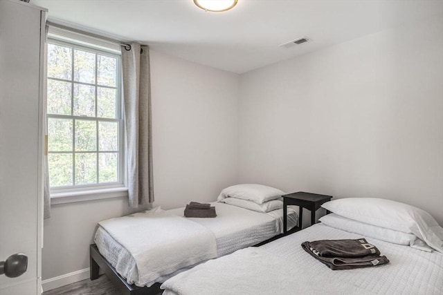 bedroom featuring multiple windows, baseboards, and wood finished floors