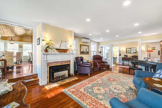 living room with a wall mounted AC, dark wood-style flooring, a fireplace with flush hearth, recessed lighting, and baseboards