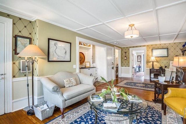 living area featuring wallpapered walls, wood finished floors, baseboards, and a wainscoted wall