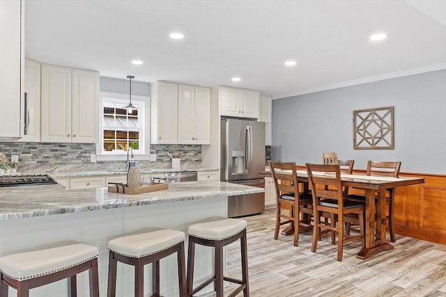 33 N Shore Rd, Westminster, MA 01473 - kitchen featuring stainless steel appliances, a breakfast bar, tasteful backsplash, ornamental molding, and light wood-type flooring