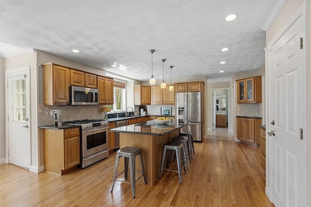 kitchen with a kitchen island, appliances with stainless steel finishes, a sink, a breakfast bar, and recessed lighting