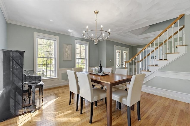 dining room with light wood-type flooring, a wainscoted wall, a notable chandelier, and stairway