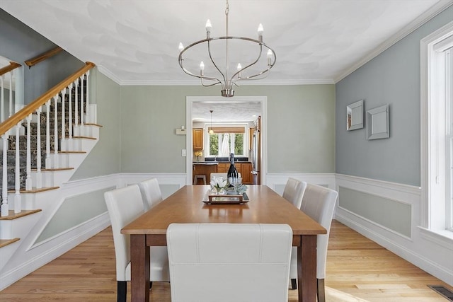 dining room with visible vents, wainscoting, light wood-type flooring, and a notable chandelier