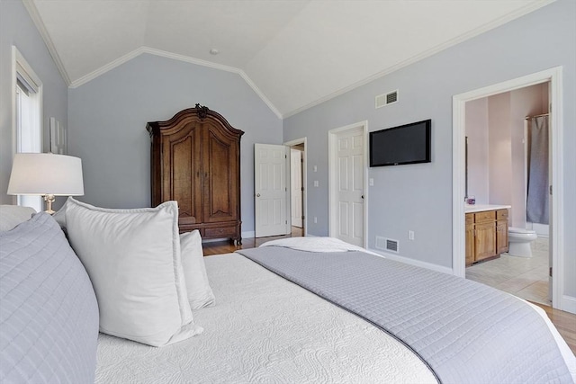 bedroom with lofted ceiling, light wood finished floors, ensuite bath, and visible vents
