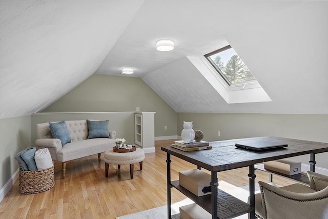 office space featuring baseboards, lofted ceiling with skylight, and light wood-type flooring