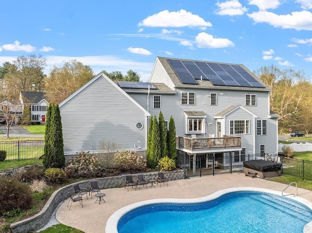 back of property featuring a hot tub, a patio, solar panels, and fence private yard