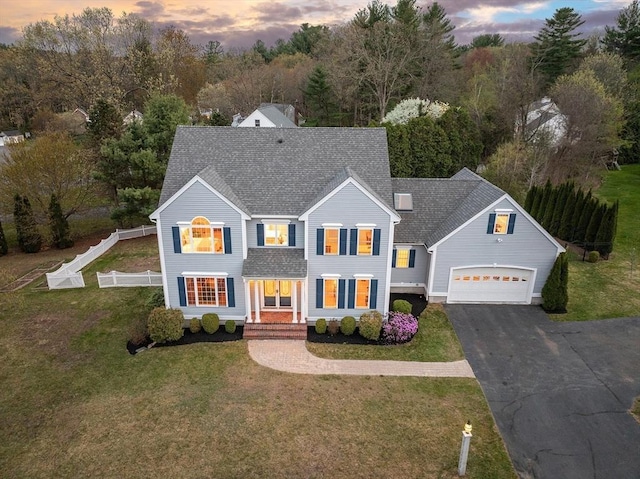 view of front of house with fence, a shingled roof, driveway, and a front yard