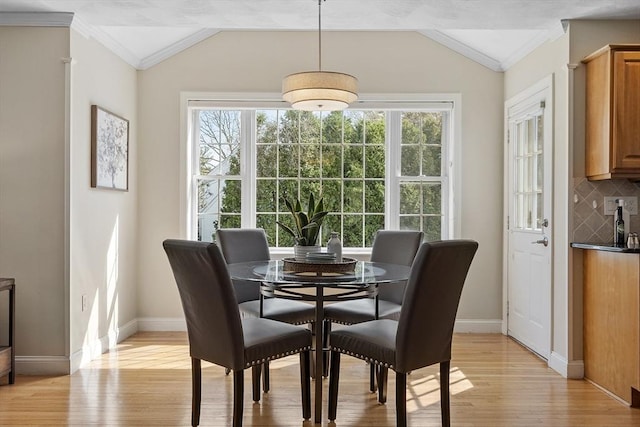 dining area featuring crown molding, light wood finished floors, and lofted ceiling