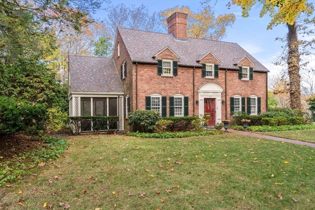 colonial-style house featuring a sunroom and a front lawn