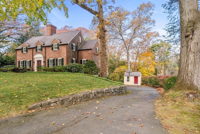 view of front of property with a front lawn and a storage shed