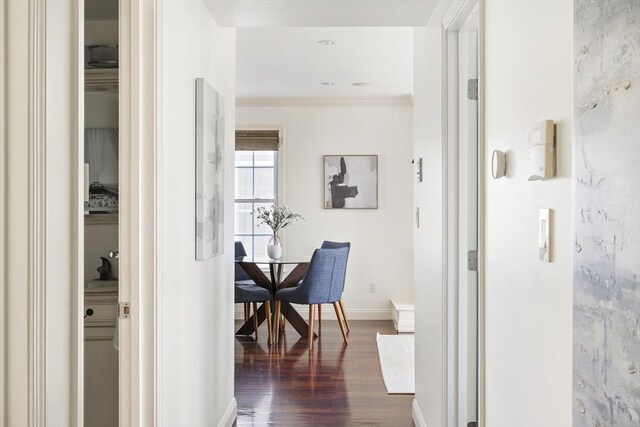 hallway with crown molding, baseboards, and dark wood-type flooring