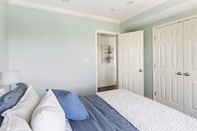 bedroom featuring crown molding, a closet, wood finished floors, and baseboards