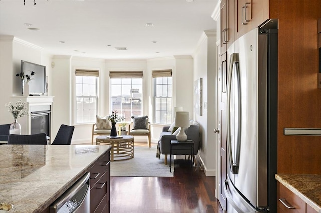 kitchen with stainless steel appliances, dark wood-style flooring, light stone countertops, and a healthy amount of sunlight