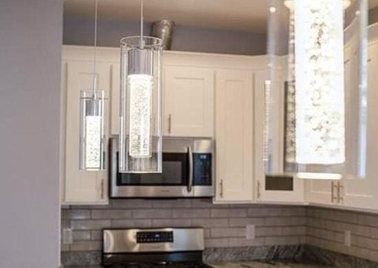 kitchen with appliances with stainless steel finishes, backsplash, a notable chandelier, white cabinets, and hanging light fixtures