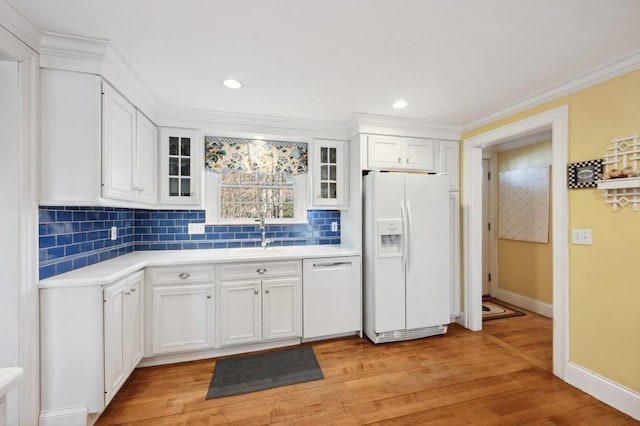 kitchen with a sink, white cabinetry, white appliances, light wood-style floors, and light countertops