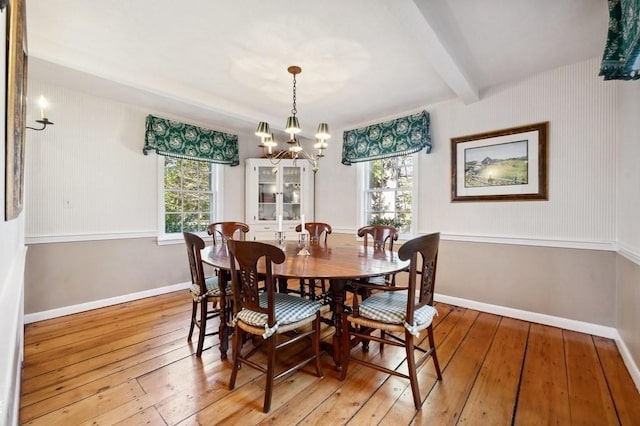 dining area featuring baseboards, beam ceiling, a chandelier, and light wood finished floors