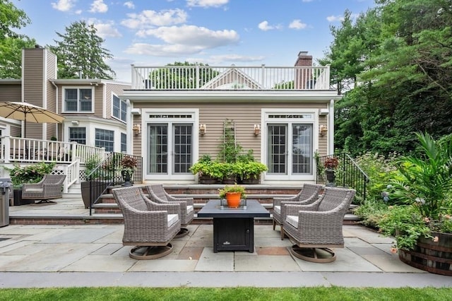 rear view of property featuring french doors, a patio, a chimney, and an outdoor hangout area