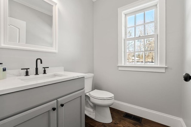 bathroom with a healthy amount of sunlight, toilet, hardwood / wood-style floors, and vanity