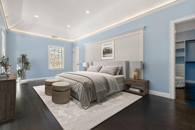 bedroom with a tray ceiling, dark hardwood / wood-style floors, and a spacious closet