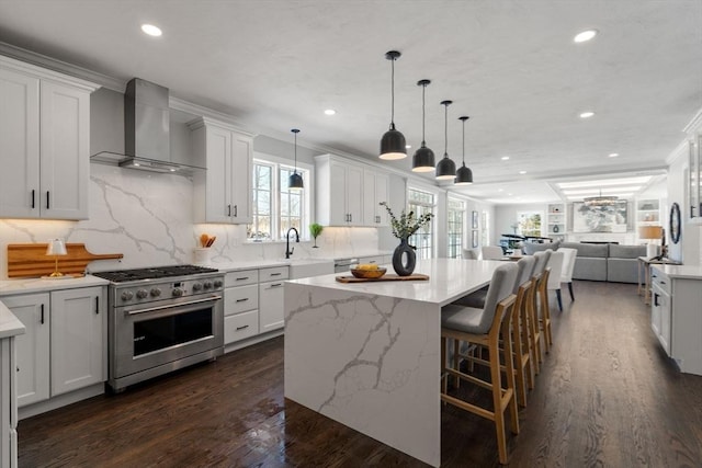 kitchen featuring white cabinetry, wall chimney range hood, a center island, and high end stainless steel range oven