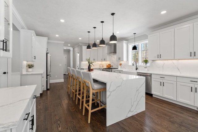 kitchen featuring hanging light fixtures, appliances with stainless steel finishes, white cabinets, and a spacious island