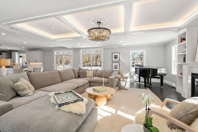 living room featuring dark wood-type flooring, coffered ceiling, a tiled fireplace, and a notable chandelier