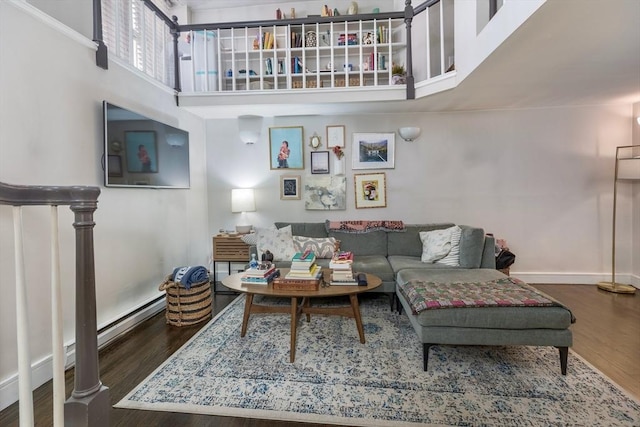 living room with wood finished floors, baseboards, and a towering ceiling
