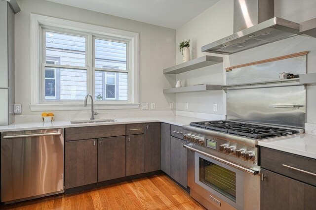 kitchen featuring appliances with stainless steel finishes, sink, wall chimney range hood, and dark brown cabinets