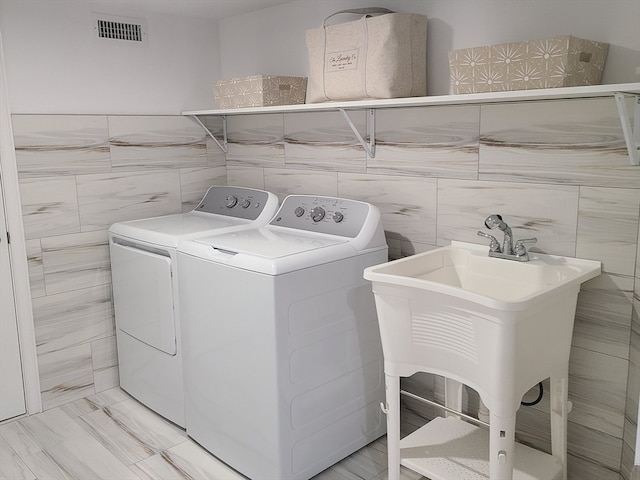 washroom with tile walls, sink, and washing machine and dryer